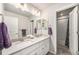 Bright bathroom featuring double sinks, white cabinets, framed mirrors, and a shower/tub combo at 7121 W Asbury Pl, Lakewood, CO 80227