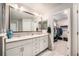 Bright bathroom features double vanity, white cabinets, framed mirror, and walk-in closet at 7121 W Asbury Pl, Lakewood, CO 80227