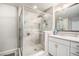 Bathroom with glass enclosed shower, brushed nickel fixtures, white cabinets, and large framed mirror at 7121 W Asbury Pl, Lakewood, CO 80227