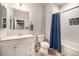 Well-lit bathroom with white vanity, updated fixtures, and shower/tub combo with blue curtain at 7121 W Asbury Pl, Lakewood, CO 80227