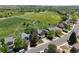 Aerial view of a blue house with a large green field, trees, and city views in a quiet suburban neighborhood at 8680 Apache Plume Dr, Parker, CO 80134
