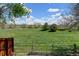 Scenic backyard view with a wooden fence bordering a vast green field under a bright, partly cloudy sky at 8680 Apache Plume Dr, Parker, CO 80134
