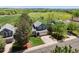 Two-story home with an attached garage, surrounded by mature trees and a green field in the distance at 8680 Apache Plume Dr, Parker, CO 80134