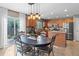 Inviting kitchen and dining area featuring wood cabinets, stainless steel appliances, island, and a stylish light fixture at 5434 S Rome St, Aurora, CO 80015