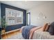 Bedroom with blue accent wall, bright windows, stylish decor, and hardwood floors for a comfortable and inviting space at 6795 W 29Th Ave, Wheat Ridge, CO 80214