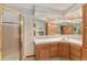 Bright bathroom features tiled countertops, oak cabinets, mirrored wall, and glass door walk-in shower at 533 Tenderfoot Dr, Larkspur, CO 80118