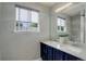 Bathroom with double sinks, a large mirror, navy blue cabinets, and a window for natural light at 5757 W Alamo Dr, Littleton, CO 80123