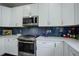 Updated kitchen featuring stainless steel appliances, white cabinets, quartz countertops, and stylish blue subway tile backsplash at 5757 W Alamo Dr, Littleton, CO 80123