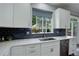 Stylish kitchen featuring white cabinets, dark blue backsplash, and stainless steel appliances at 5757 W Alamo Dr, Littleton, CO 80123