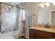 Well-lit bathroom features a granite countertop, dark wood vanity, and a shower with gray textured tiles at 2253 S Fox St, Denver, CO 80223