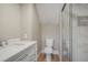 Well-lit bathroom featuring white vanity, white toilet, and a shower with glass doors and marble tiling at 2253 S Fox St, Denver, CO 80223