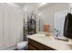 Bright bathroom featuring a shower with curtain, dark wood vanity, and decorative shelving for storage at 132 Ambrose St, Erie, CO 80516