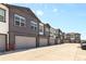 Row of newly-built townhomes with attached garages, modern architectural details, and ample parking at 132 Ambrose St, Erie, CO 80516
