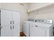 Well-organized laundry room with modern washer and dryer, storage cabinets, and wood-look flooring at 132 Ambrose St, Erie, CO 80516