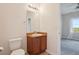 Bathroom featuring a vanity, mirror with lighting, toilet, and view of the bedroom at 12921 Grant Cir # B, Thornton, CO 80241
