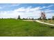 Grassy community playground area with swings, benches and walking path, perfect for outdoor fun at 4880 River Landing Ave, Firestone, CO 80504