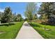 Scenic paved walkway through a grassy area with mature trees on a sunny day with clear blue sky at 13030 King Cir, Broomfield, CO 80020