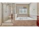 This bathroom has a tiled surround tub, a window and a tiled shower at 5078 Zion Ct, Castle Rock, CO 80109