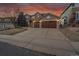 Inviting two-story home featuring a well-kept lawn, mature trees, and a spacious two-car garage at dusk at 9845 Glenstone Trl, Highlands Ranch, CO 80130