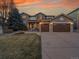 Beautiful two-story home with a manicured lawn, mature trees, and a two-car garage, set against a colorful sunset at 9845 Glenstone Trl, Highlands Ranch, CO 80130