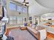 Bright living room with tall windows, vaulted ceiling, hardwood floors, and a stone fireplace at 9845 Glenstone Trl, Highlands Ranch, CO 80130