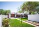 Red brick single-story home with a well-maintained lawn and a white fence-lined backyard on a sunny day at 509 Newland St, Lakewood, CO 80226