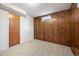 Basement corner with wood paneling, carpet and one window with a door offering a warm and inviting atmosphere at 509 Newland St, Lakewood, CO 80226