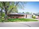 Charming brick home featuring a well-kept lawn, lush landscaping, and a modern solar panel system on the roof at 509 Newland St, Lakewood, CO 80226