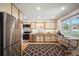 Well-lit kitchen featuring stainless steel appliances, light cabinets, and a window overlooking the yard at 509 Newland St, Lakewood, CO 80226