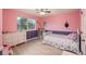 Bright bedroom featuring pink walls, white furniture, a large window, and light wood flooring at 16667 Tin Cup Ct, Parker, CO 80134