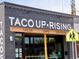 Charming taco shop with the words 'Taco Uprising' painted in white over the grey brick facade at 2737 N Marion St, Denver, CO 80205