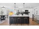Bright kitchen features modern black and white cabinets, stainless steel appliances, and an island with bar stool seating at 290 Beryl Way, Broomfield, CO 80020