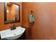 Bathroom featuring a white sink, mirror, dark fixtures, and textured orange walls at 1811 S Quebec Way # 187, Denver, CO 80231