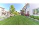 Expansive backyard featuring a lush lawn, white fence, mature trees, and landscaping at 16383 Ute Peak Way, Broomfield, CO 80023