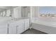 Bright bathroom featuring a large vanity with double sinks, a soaking tub with a view, and sleek, modern fixtures at 16383 Ute Peak Way, Broomfield, CO 80023