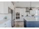 Bright kitchen boasts white cabinets, stainless steel appliances, and a large island with a blue base at 16383 Ute Peak Way, Broomfield, CO 80023