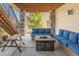 Cozy covered outdoor patio with stone columns, fire pit, picnic table and comfortable blue cushioned seating at 16383 Ute Peak Way, Broomfield, CO 80023