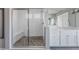 Spa-like bathroom featuring a walk-in shower with pebble flooring, a glass enclosure, and a double sink vanity at 16383 Ute Peak Way, Broomfield, CO 80023