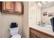 Cozy half bathroom with a wooden vanity, sink, and toilet with towel basket at 2777 E Geddes Ave, Centennial, CO 80122