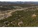 Stunning aerial view of a home nestled amongst trees in a mountain community at 8724 Armadillo Trl, Evergreen, CO 80439