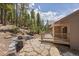 Backyard area featuring a stone patio with an outdoor grill, and surrounding trees at 8724 Armadillo Trl, Evergreen, CO 80439
