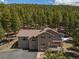 A two-story home with a spacious deck is surrounded by a lush, green landscape at 8724 Armadillo Trl, Evergreen, CO 80439