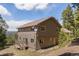 Exterior view displaying the back of the home, with many windows, a deck and well-kept landscaping at 8724 Armadillo Trl, Evergreen, CO 80439