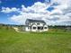 Expansive backyard with a modern farmhouse, patio, and well-maintained lawn at 609 Pioneer Camp Vw, Palmer Lake, CO 80133