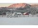 Winter scene of a snow-covered property with mountain backdrop and wooden fence at 609 Pioneer Camp Vw, Palmer Lake, CO 80133