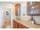 Butlers pantry with wood cabinets, granite counters, and glass-front cabinets with natural light at 19096 W 53Rd Pl, Golden, CO 80403