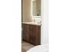 A bathroom vanity with a wooden cabinet, bronze hardware, and a lighted mirror at 4631 Zuni St, Denver, CO 80211