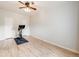 Minimalist bedroom with hardwood flooring, ceiling fan, and exercise bike against a white wall at 4250 S Olive St # 108, Denver, CO 80237