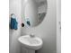 A minimalist pedestal sink in a powder room, complemented by a round mirror at 933 Canal West Dr, Brighton, CO 80603