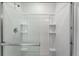 Modern bathroom shower featuring sleek fixtures, glass doors and integrated shelving at 933 Canal West Dr, Brighton, CO 80603